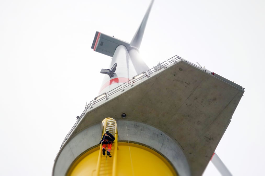 An offshore wind worker climbing on a wind turbine on a ladder