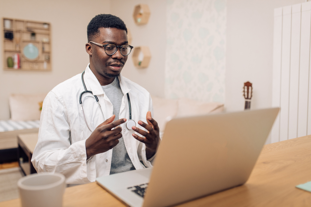 A picture of an African American young doctor working online with his patients.