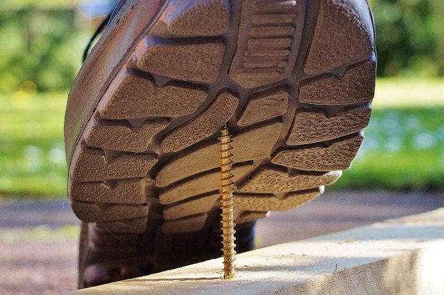 A picture of a foot stepping on a nail on a construction project.